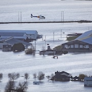 Un hélicoptère de la Gendarmerie royale du Canada survole des fermes inondées de la région de Sumas Prairie.