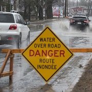 Panneau routier avertissant qu'une route est partiellement inondé.