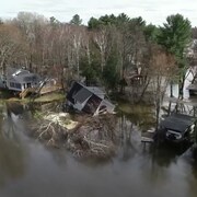 Des maisons inondées vue du ciel. L'une d'elle s'est affaisée dans l'eau.