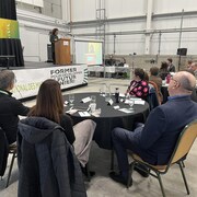 Des gens assis à une table écoutent une conférence lors du colloque.