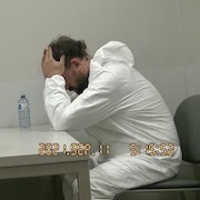 Le policier, stylo à la main, parle au suspect.