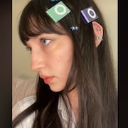 Une jeune femme porte deux iPod Shuffle en guise de barrettes dans les cheveux. 