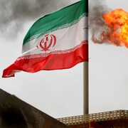 Un drapeau iranien flotte devant une cheminée crachant des flammes vers le ciel, sur la réserve de pétrole Soroush, près du golfe Persique, en Iran.