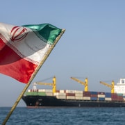 Un drapeau de l'Iran flotte devant un bateau sur l'eau.