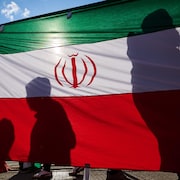 Des manifestants passent devant un drapeau national iranien.