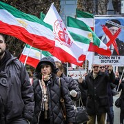 Un groupe de manifestants avec des drapeaux iraniens et des signes ouvertement contre le régime islamique iranien.