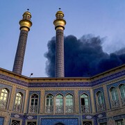 De la fumée s'élève derrière un immeuble.