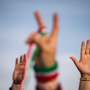 Des manifestants iraniens font le signe de la victoire lors d'une manifestation contre la République islamique à Washington.