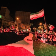 De nombreuses personnes brandissent des drapeaux de l'Iran et de la Palestine.