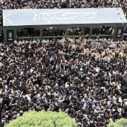 Une foule immense entourant un cortège funéraire.