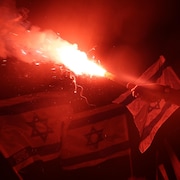 Des manifestants portant des drapeaux et un fumigène