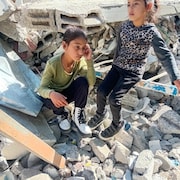 Deux jeunes filles assises sur les décombres d'une maison bombardée à Gaza.