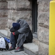 Une homme assis sur une marche, la tête entre les bras.