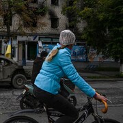 Une femme roule à vélo dans une rue d'Izioum, en Ukraine.