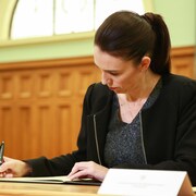 La première ministre Jacinda Ardern signe un document au Parlement.