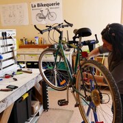 Jacinthe Wiebe répare un vélo en avril 2023 dans le nouveau local de l'atelier de réparation de vélos La Bikequerie, à Steinbach. 