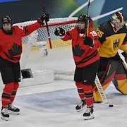 Les deux joueuses lèvent les bras près du filet allemand.