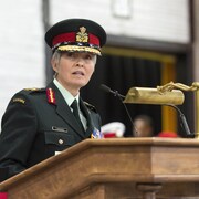 La générale Carignan prononçant un discours sur une tribune lors d'une cérémonie militaire.