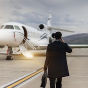 Un homme d'affaires qui parle au téléphone marche vers un jet privé sur un tarmac.