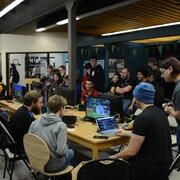 Des gens sont rassemblés autour d'écrans d'ordinateur dans une salle dédiée aux jeux vidéo. 