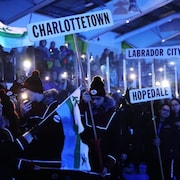 Des athlètes tenant des drapeaux et des affiches participent à la cérémonie d'ouverture des Jeux d'hiver du Labrador.