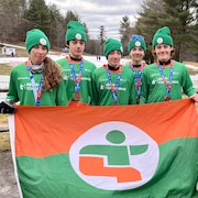 Cinq jeunes athlètes, médailles au cou, posent pour la caméra en montrant le drapeau de leur région.
