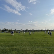 Des jeunes jouent au soccer sur un terrain gazonné.