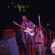 Jimmy Hendrix chante et joue de la guitare sur scène, sur une photo d'archives datant de 1969. 