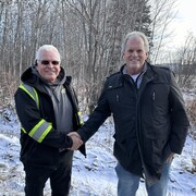 Les deux hommes se serrent la main sur un sentier de motoneige.