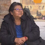 Une femme assise devant une résidence.