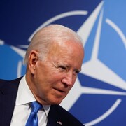 Gros plan de Biden devant un logo de l'OTAN.
