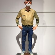Une scupture représentant l'artiste Joe Fafard, debout, le téléphone dépassant de la poche de sa chemise.