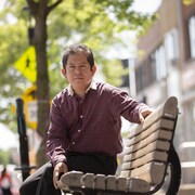 Joni Ismael Velazquez assis sur un banc public.