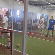 quatre hommes, dans un local transparent, jouent au jorkyball.
