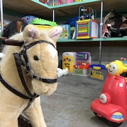 Un cheval à bascule et de nombreux autres jouets sont rassemblés dans un entrepôt.