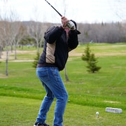 Un homme s'apprête à frapper une balle de golf.  