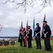 Cinq membres de la légion 76 de Sudbury tiennent les drapeaux en rang pour le Jour du Souvenir.