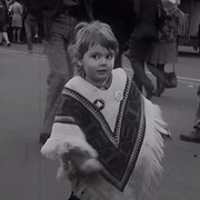 Enfant d'environ deux ans qui danse dans la rue. Il porte un poncho.