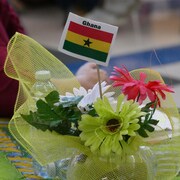 Un centre de table rempli de fleurs avec un petit drapeau du Ghana.