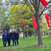 Quatre femmes rassemblées dans un parc ou sont accrochées des robes rouges. 