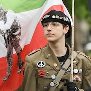 Une personne habillée en militaire et brandissant un drapeau des patriotes, le 19 mai, à la marche pour la Journée nationale des patriotes. 