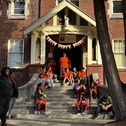 Des jeunes portent des chandails orange et se tiennent debout devant l'entrée de l'école catholique St Thomas Aquinas.  