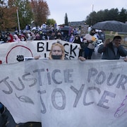 Des personnes tiennent une banderole sur laquelle on peut lire : Justice pour Joyce.