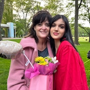Les deux femmes posent dans un parc avec un cadeau dans les mains.