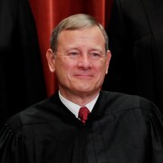 John Roberts, portant sa toge de juge et souriant à la caméra