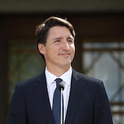 Justin Trudeau fait un sourire en tournant la tête à sa gauche. 