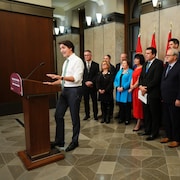 Justin Trudeau parle derrière un lutrin, tandis qu'on voit un groupe de dignitaires qui l'écoutent derrière lui.