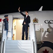 Justin Trudeau salue de la main avant de monter à bord d'un avion du gouvernement du Canada.