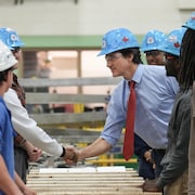 Justin Trudeau (au centre) rencontre des charpentiers avant de parler de nouvelles solutions en matière de logement au centre de formation CCAT à Woodbridge, en Ontario, le vendredi 12 avril 2024.