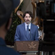 Le premier ministre Justin Trudeau debout derrière un lutrin et devant une caméra de télévision.